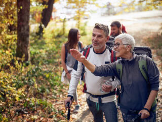 An elderly couple at hiking through the woods looking for the trail